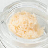 A close up of Candyland budder in a jar; it's pale vanilla in colour and crumbly in texture.