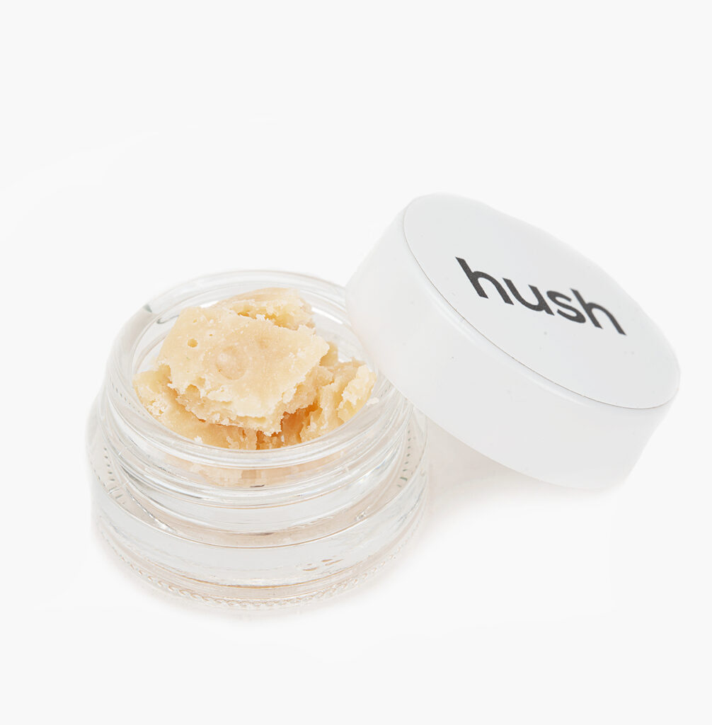 A small jar of White Wedding THC budder; the contents are pale vanilla in colour and crumbly in texture.