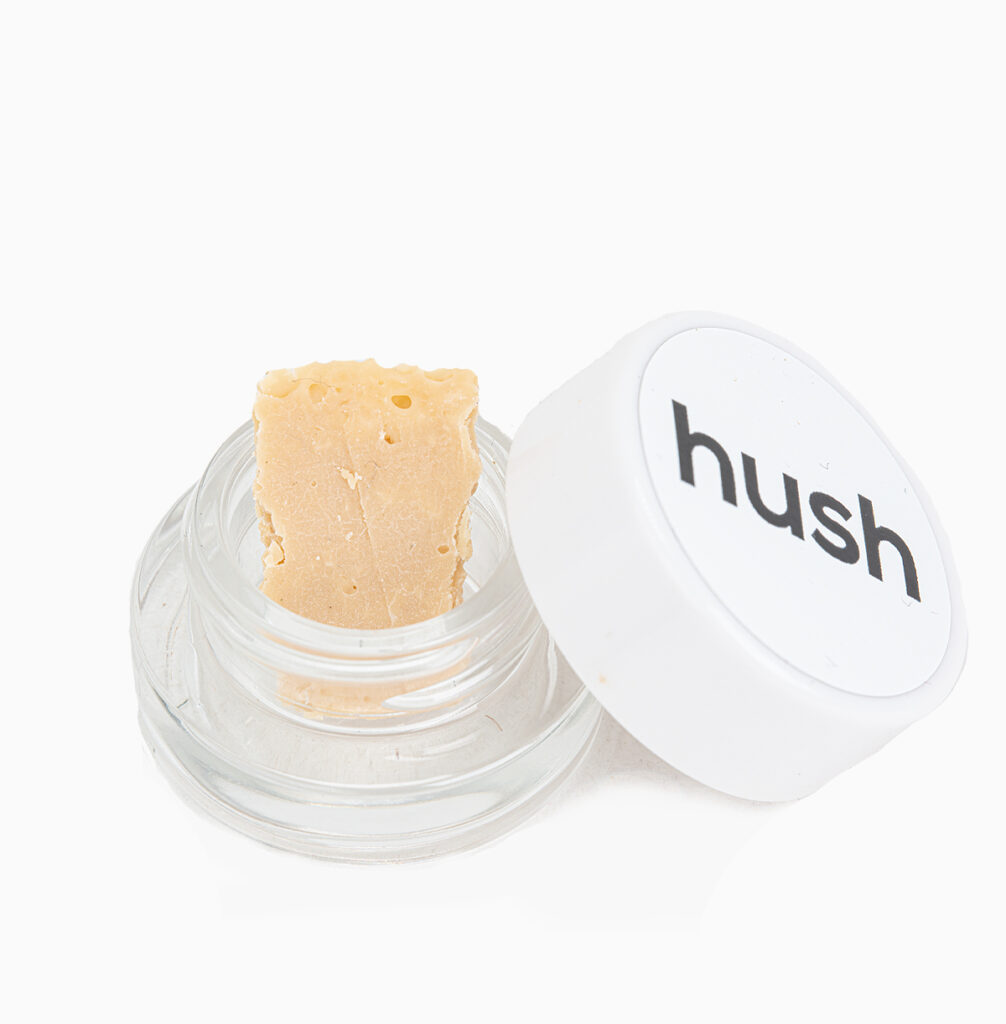 A small jar of Blackberry Kush budder produced by Hush; its dense and pale vanilla in colour.