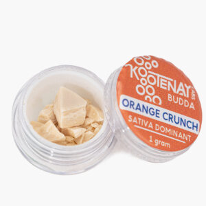 An open 1g jar of Orange Crunch budder produced by Kootenay Labs; contents are pale straw coloured and waxy in texture.
